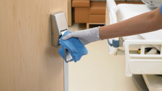 Environmental Services staff cleans door handle in a hospital